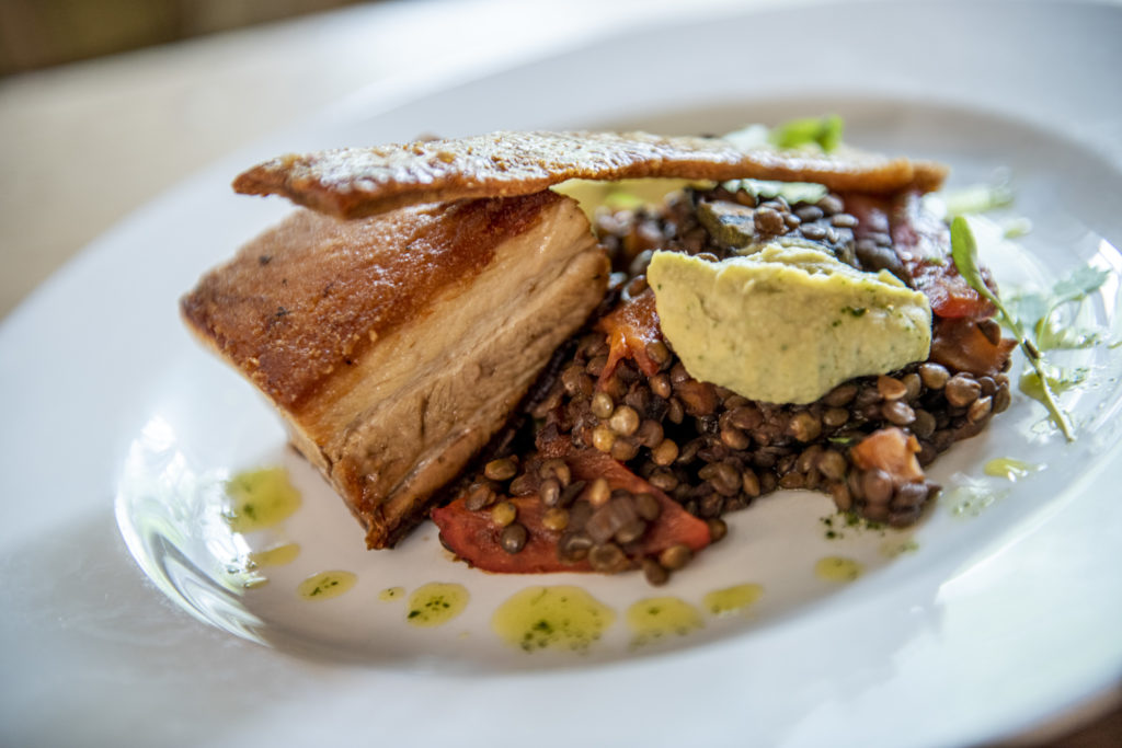 Crispy pork belly served with lentils, vegetables and herb butter