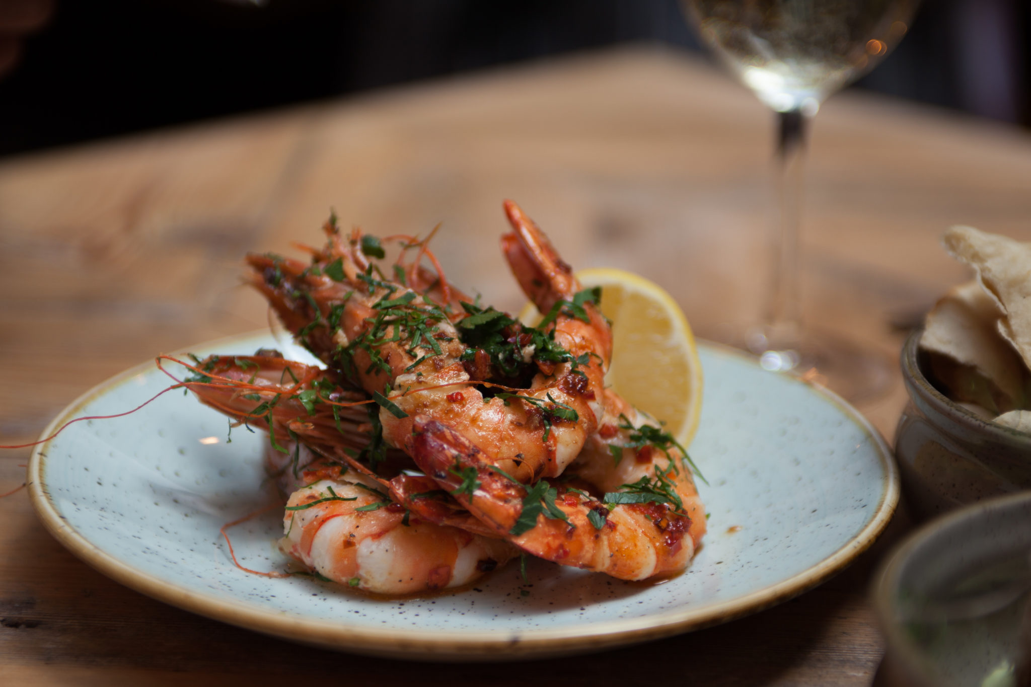 Grilled prawns topped with herbs and served with a lemon wedge