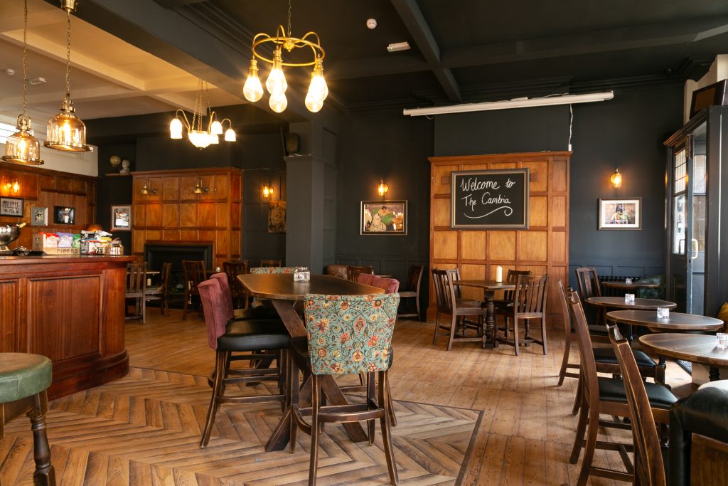 Dining area at The Cambria with wooden tables, chairs and a welcome chalkboard