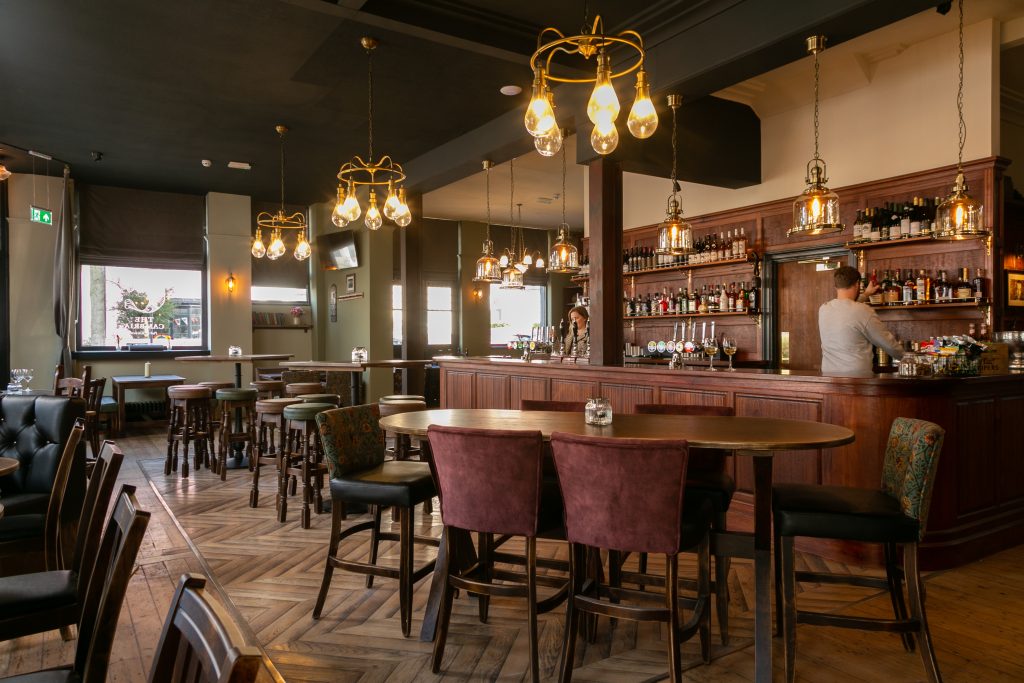 Bar and seating area inside The Cambria with wooden floors and hanging lights