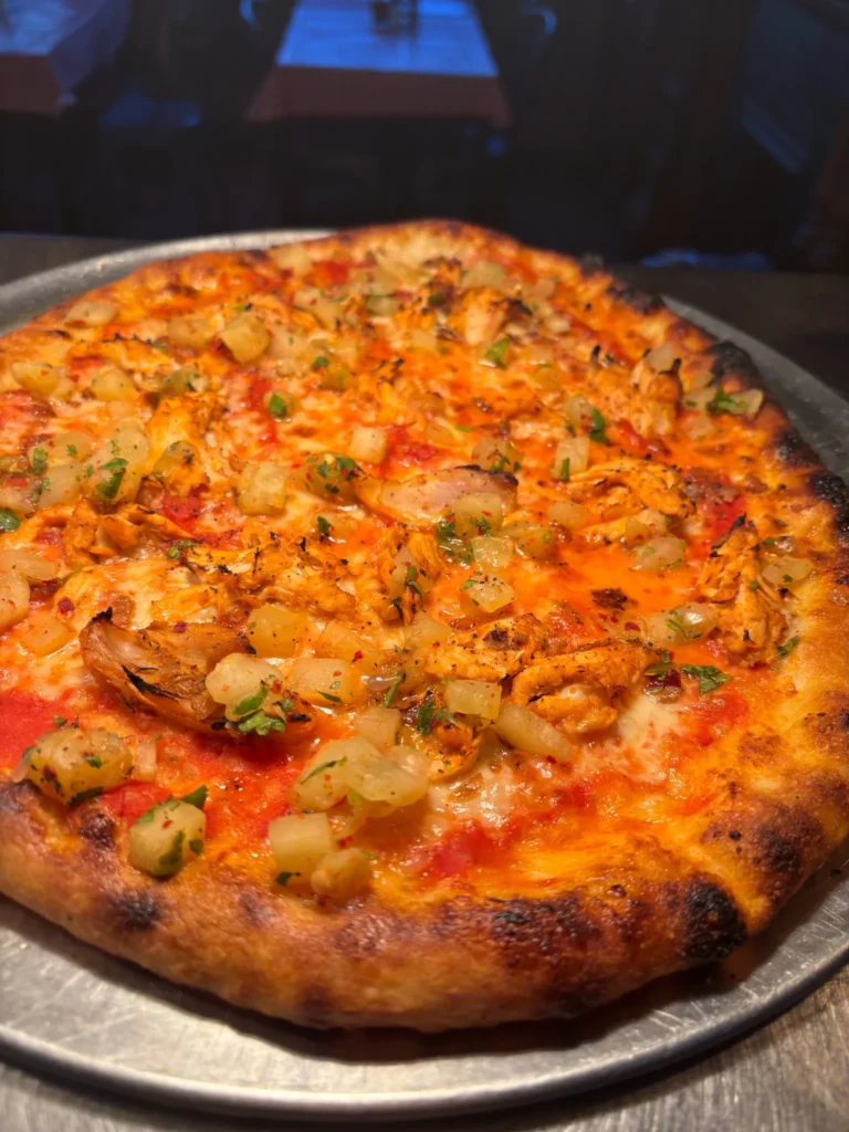 Pizza topped with chicken, onion and herbs
