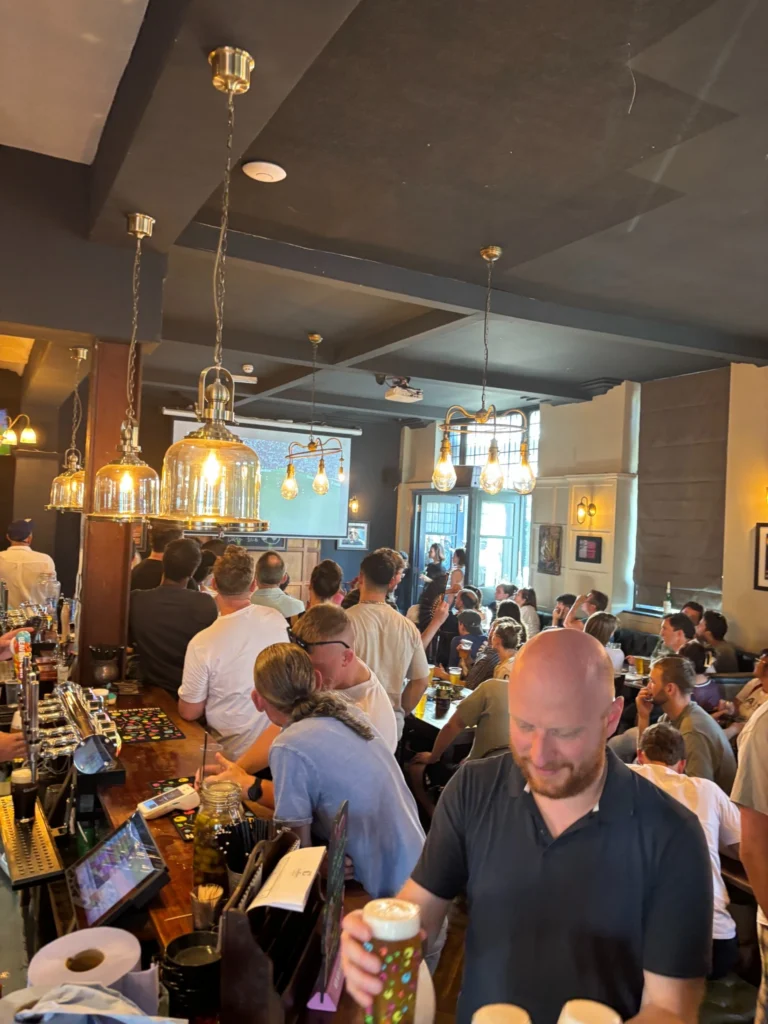Packed pub with guests watching live sport from the bar and tables
