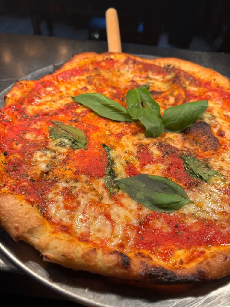 Margherita pizza topped with tomato, melted cheese and fresh basil