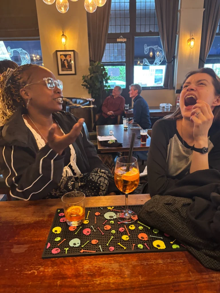 Two friends laughing together over drinks at The Cambria